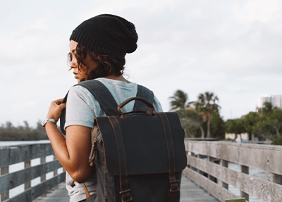 woman carrying gray backpack and long board during daytime
